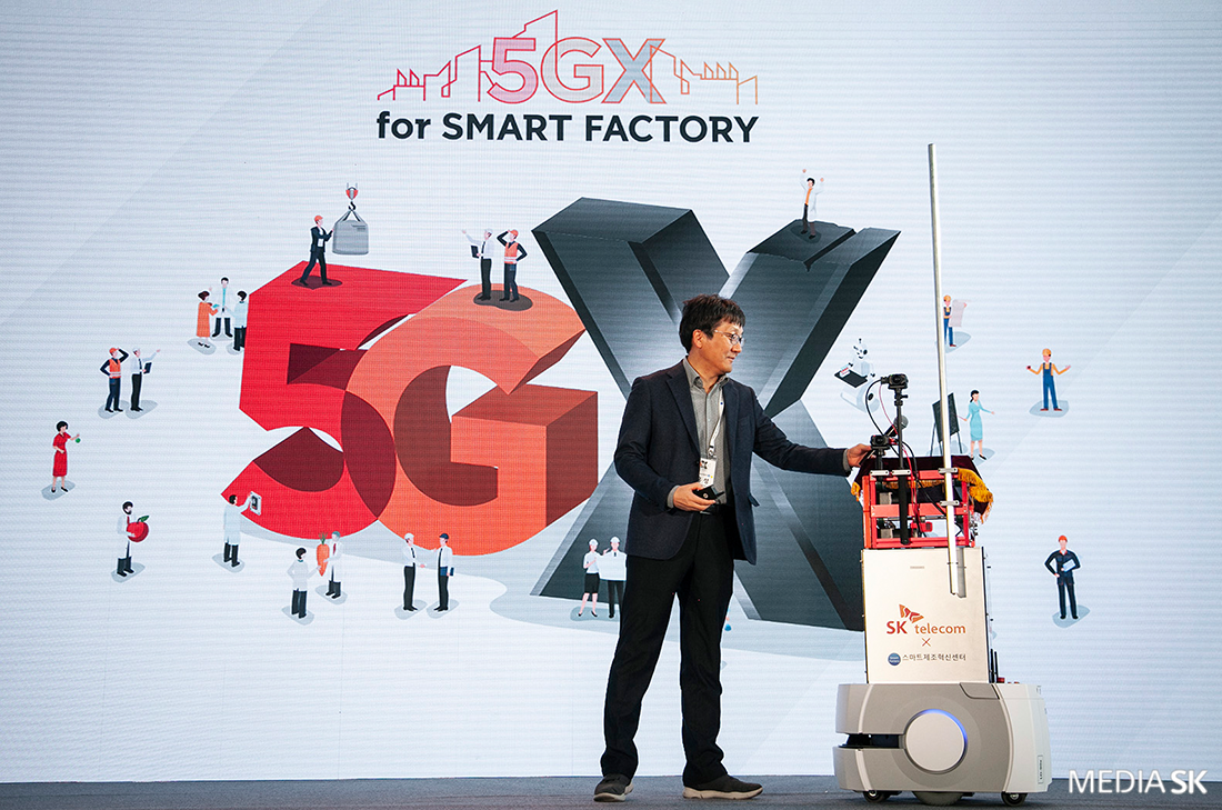 장홍성 SK텔레콤 IoT/Data사업단장이 5G 소형 자율주행로봇이 전달하는 마이크를 받고 있다.